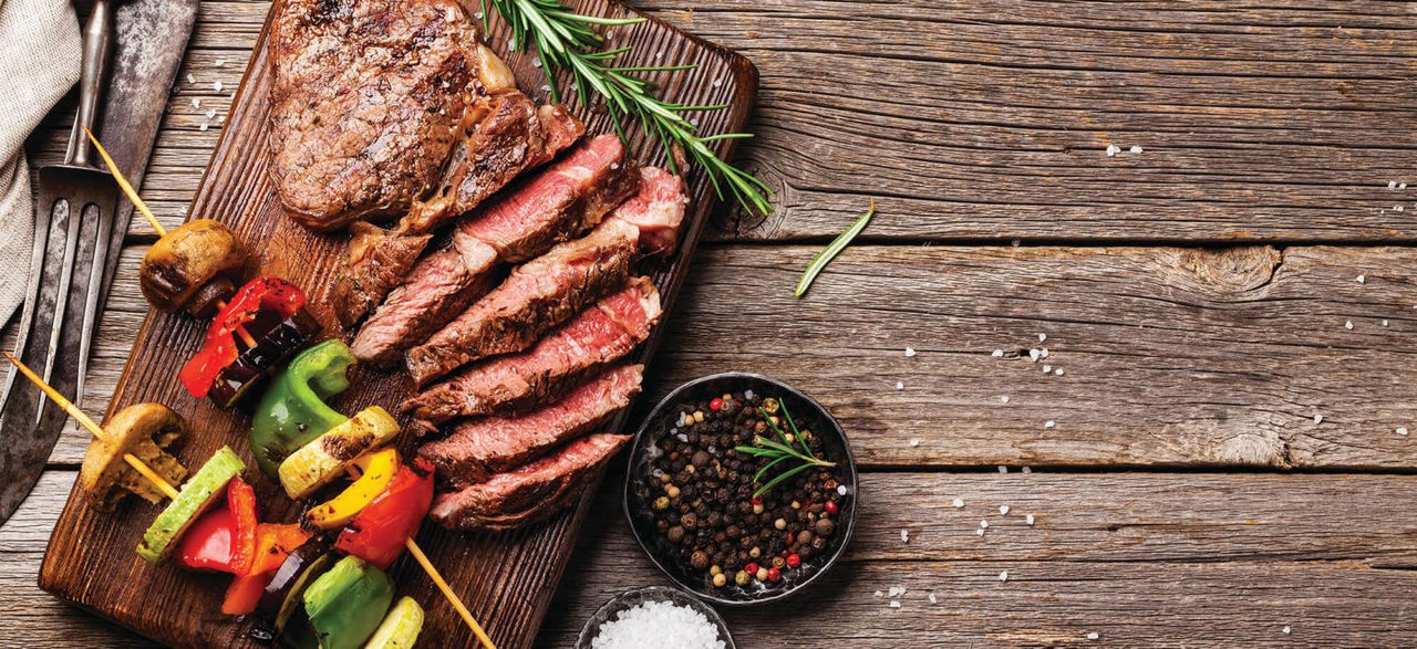 Cooked, cut steak on wooden cutting board